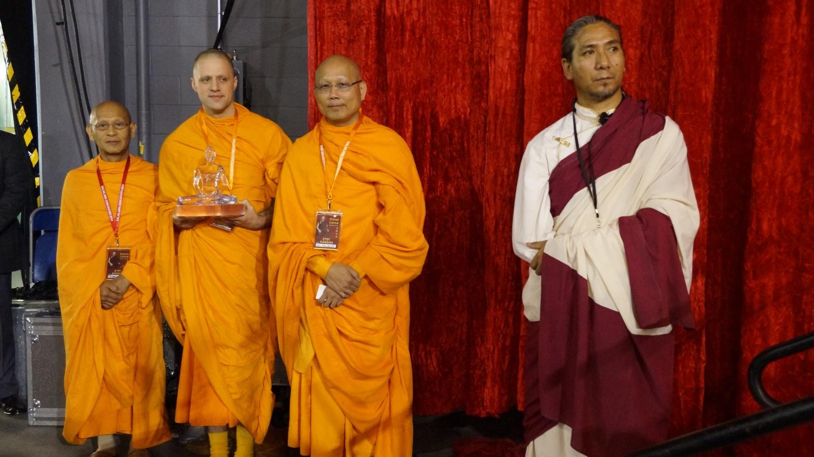 Monks in orange robes with a guest in white and maroon robes