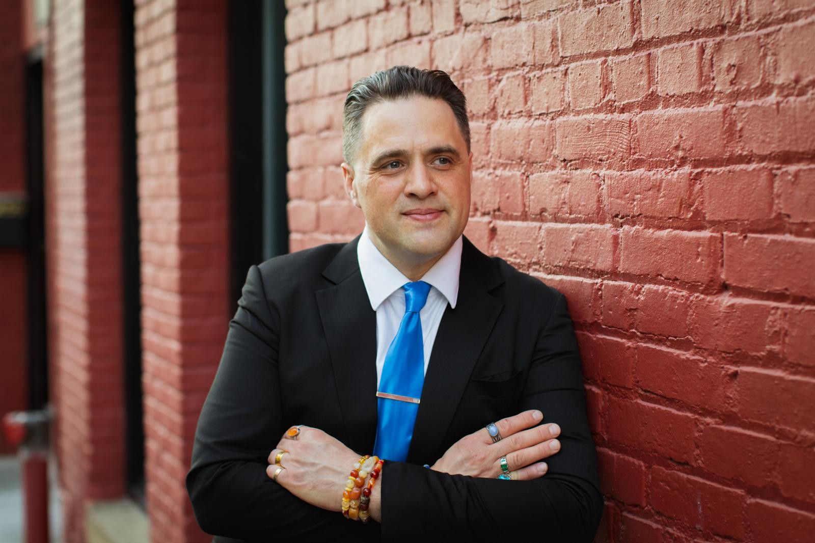 Steve Pinney Jr, life coach, arms crossed against a red brick wall in Tacoma, Washington