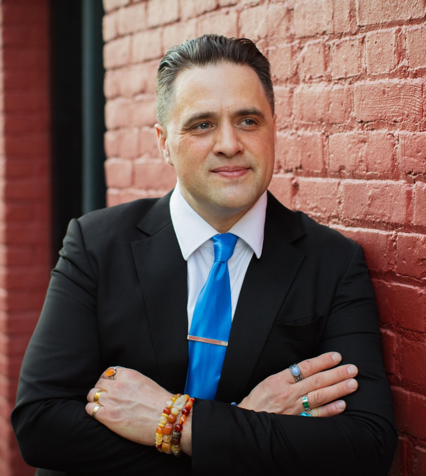 Steve Pinney Jr, life and leadership coach, arms crossed against a red brick wall