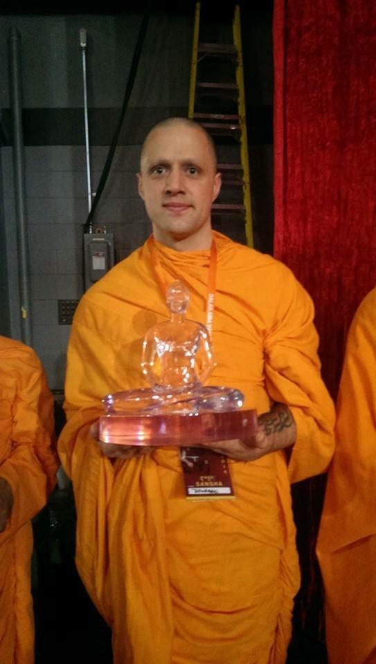 Steve Pinney Jr as a Buddhist monk holding a crystal award