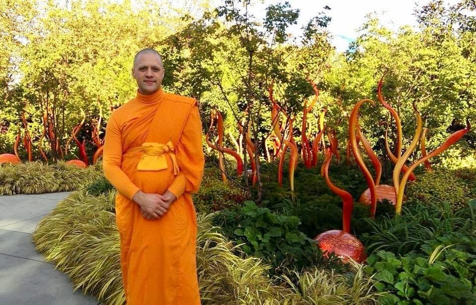 Steve Pinney Jr as a monk in a garden with red glass sculptures