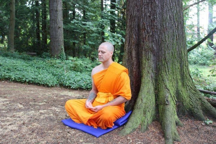 Steve Pinney Jr as a monk, meditating at the foot of a large tree in a forest