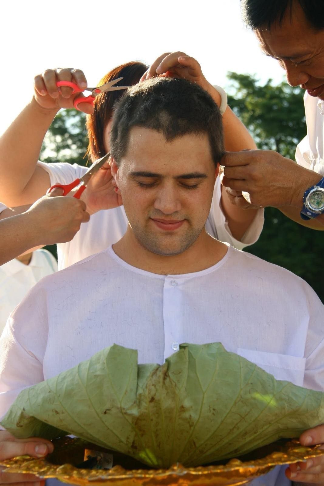 Steve Pinney Jr in white during an ordination ceremony as his hair is cut