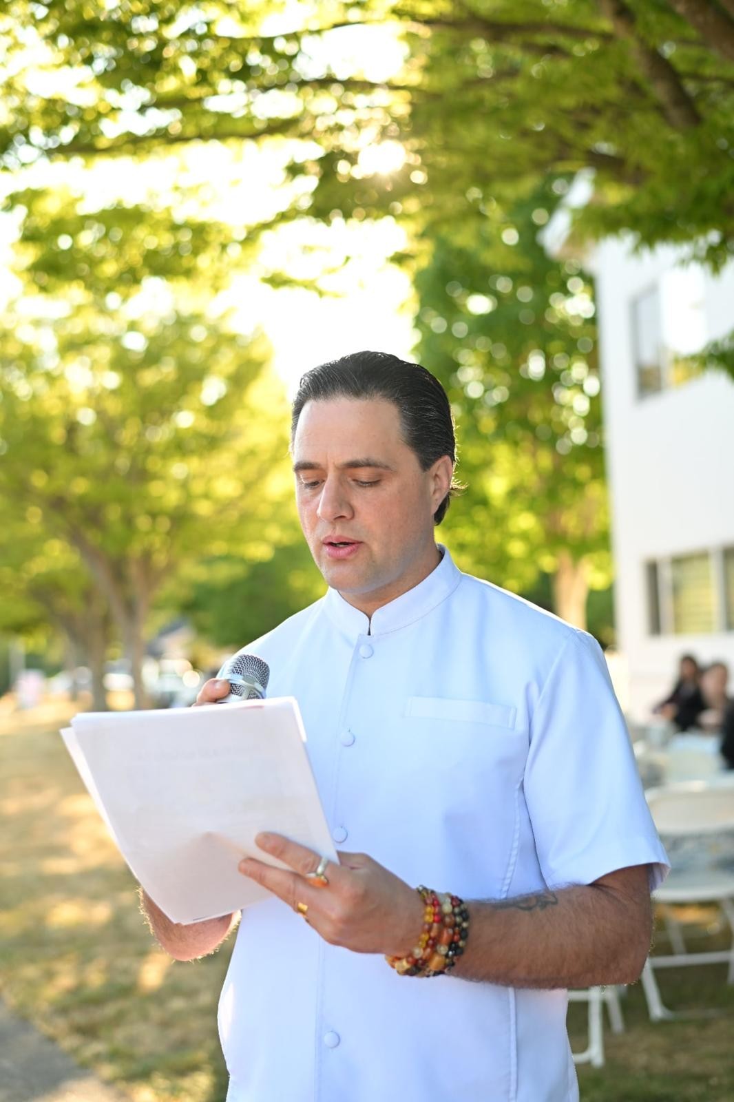 Steve Pinney Jr reading from a page at an outdoor ceremony