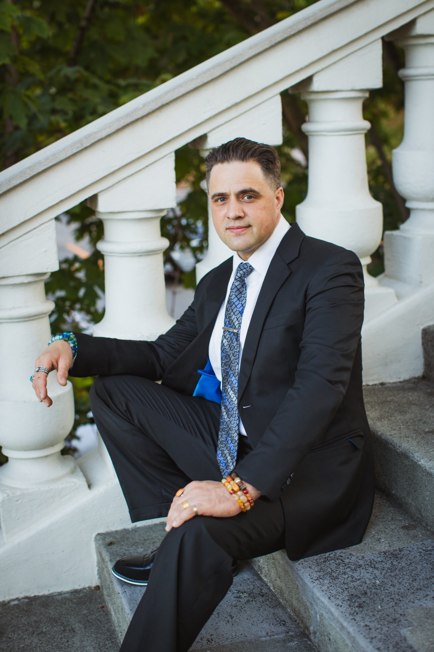 Steve Pinney Jr, life coach, seated on stone steps in a dark suit