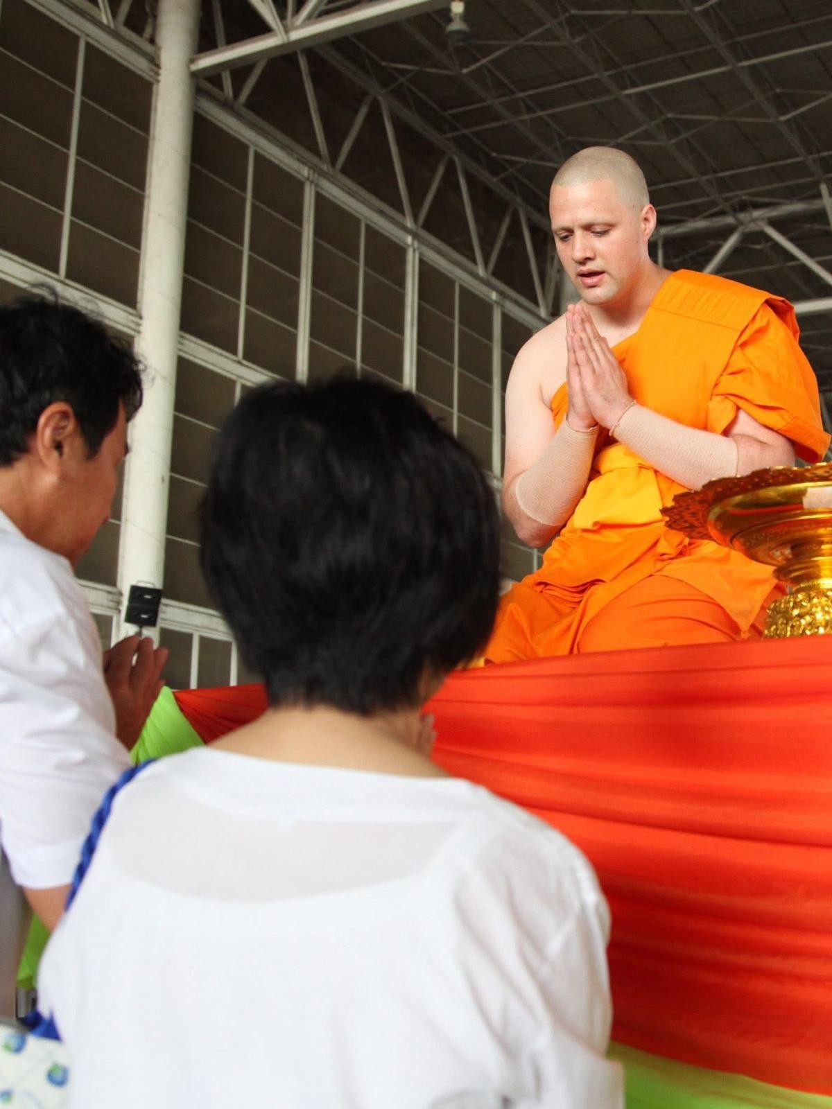 Steve Pinney Jr as a young monk, hands pressed together, blessing a visitor